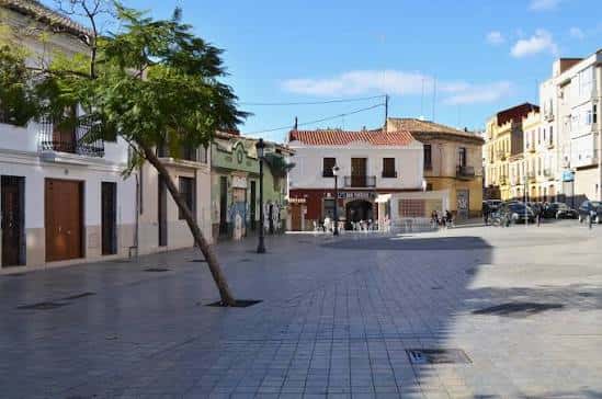 Plaza de Patraix con edificios históricos y árboles en un día soleado