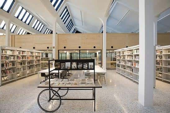 Interior luminoso de la Biblioteca Montserrat Abelló con estanterías de madera y techo a dos aguas