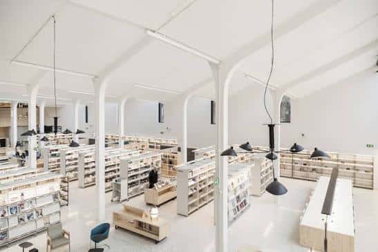 Amplio salón de lectura con columnas blancas y lámparas colgantes