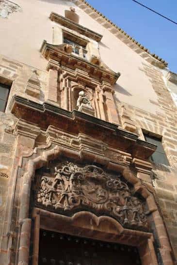 Detalle del portal principal con relieve ornamental y estatua en hornacina