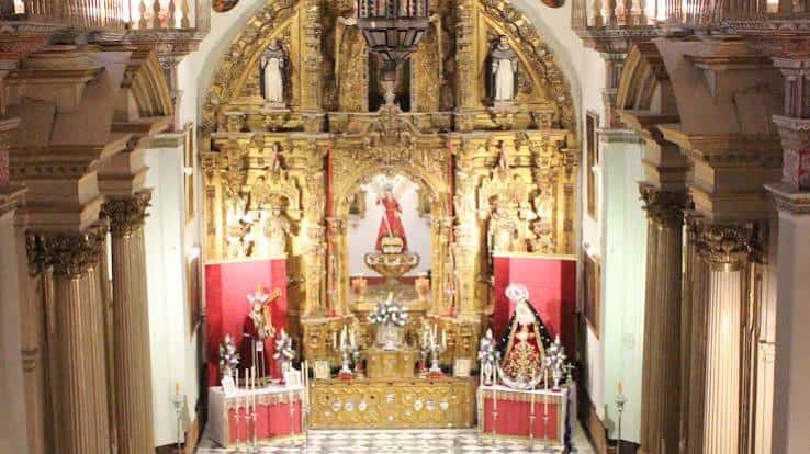 Vista del altar principal de la Basílica con retablo dorado y decoración festiva