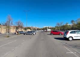 Plaza de aparcamiento al aire libre con coches y árboles en un día soleado