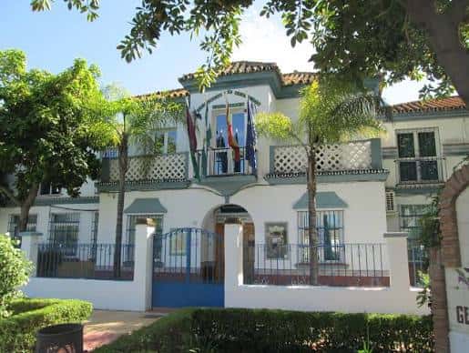 Fachada principal de la Junta Municipal de Distrito Churriana con banderas y jardines