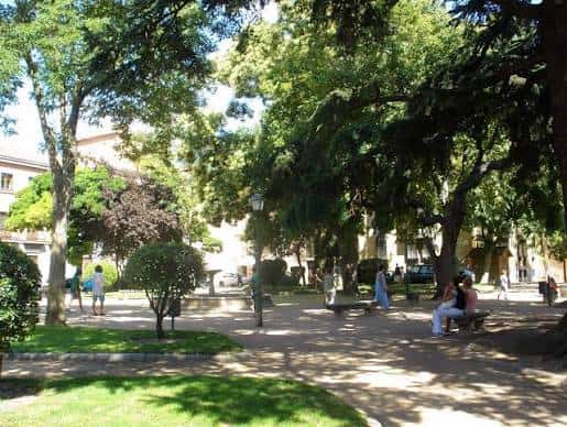 Vista arbolada de la plaza con personas paseando y bancos