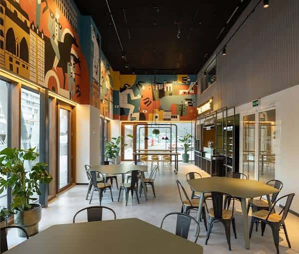 Sala de eventos o restaurante interior con murales coloridos y mesas modernas