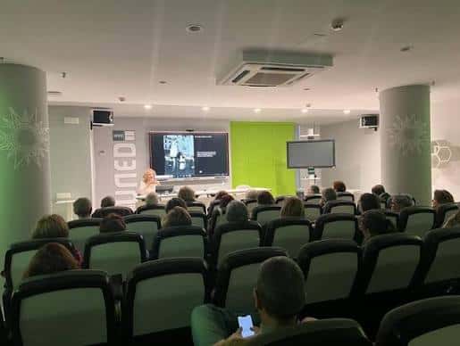 Aula magistral con pantalla y asistentes durante una sesión