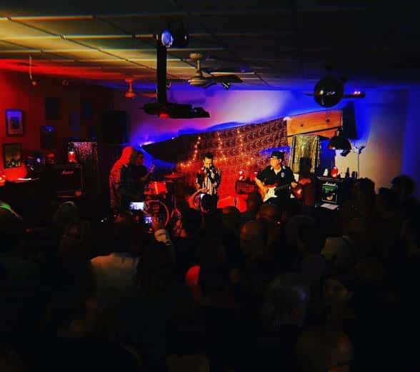 Concierto en vivo con banda tocando en el escenario bajo luces de colores