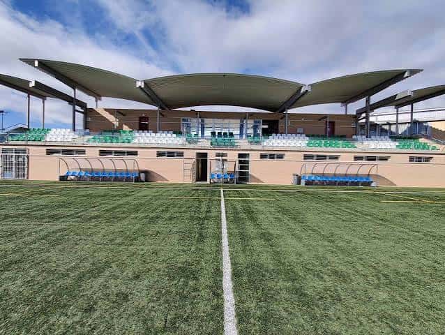 Gradas principales del estadio con techo ondulado y asientos en verde y blanco