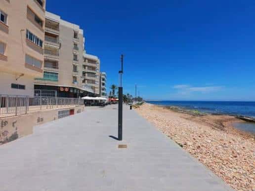Paseo marítimo junto a la playa con edificios residenciales al fondo