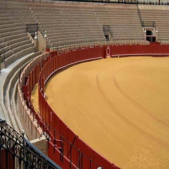 Vista del ruedo de la plaza de toros con gradas vacías y barrera roja
