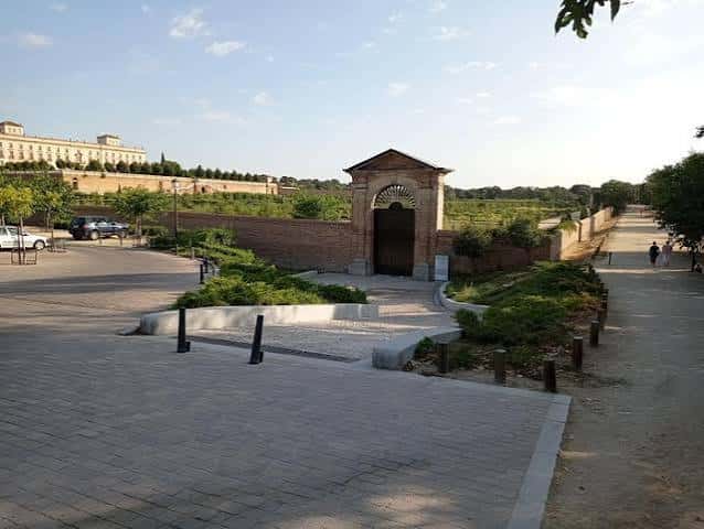 Vista amplia del paseo con puerta de acceso y edificio al fondo