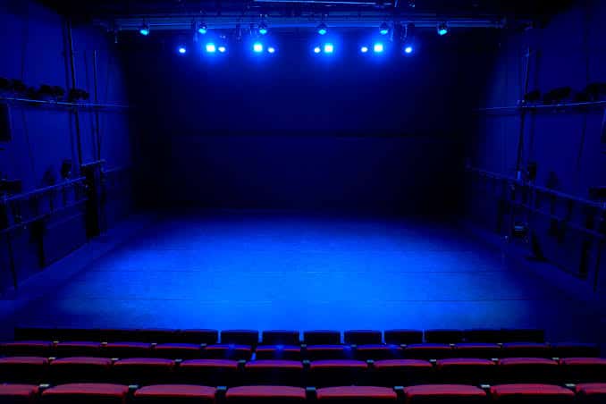 Vista del escenario principal con iluminación azul y butacas rojas