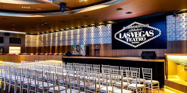 Sala principal del Teatro Las Vegas con sillas blancas dispuestas para evento y logotipo en pantalla