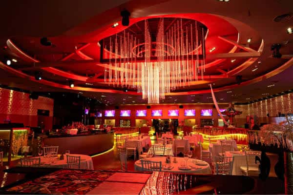 Interior del teatro decorado con iluminación roja y mesas de cena para celebración