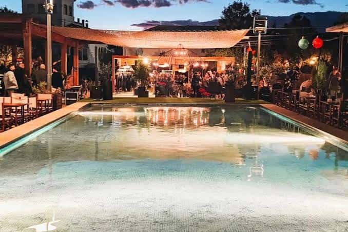 Evento al atardecer con piscina iluminada y zona de recepción en el jardín