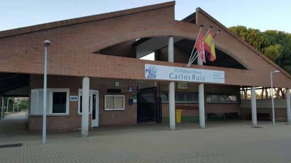 Fachada principal del Polideportivo Municipal Carlos Ruiz con banderas y señalización clara