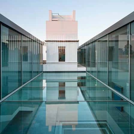 Patio interior moderno con suelo de cristal y estructura contemporánea