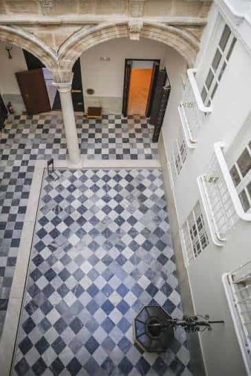 Vista cenital del patio central con baldosas a cuadros y arcos históricos