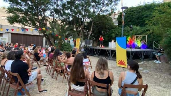 Evento al aire libre en el patio de la Casa de la Palmera con escenario y público