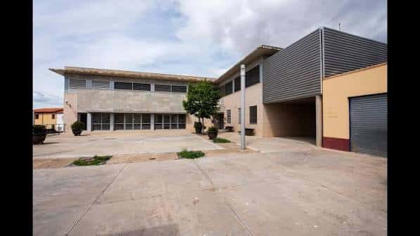 Vista exterior lateral del edificio con zona pavimentada y entrada secundaria