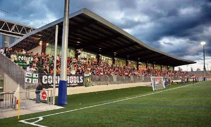Estadio lleno de aficionados durante un partido, con pancartas y ambiente festivo
