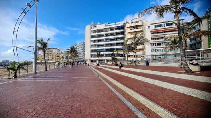 Paseo marítimo de la plaza con edificios residenciales al fondo y personas caminando