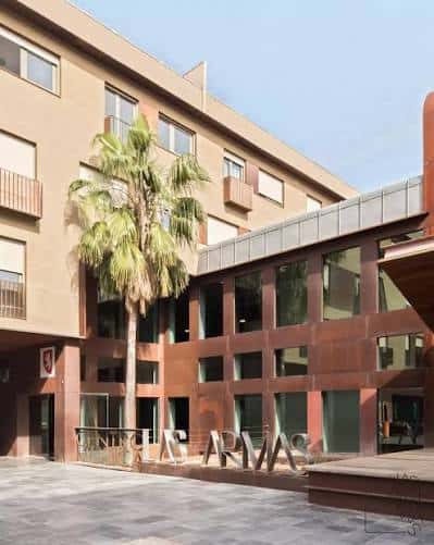 Fachada moderna del Espacio Cultural Las Armas con palmera