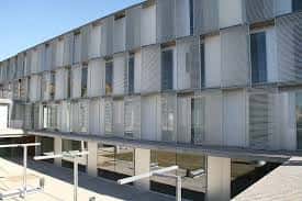 Fachada lateral del edificio con estructura de lamas metálicas y ventanas grandes