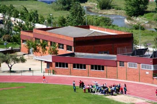 Fachada del edificio principal de ladrillo rojo junto a la pista de atletismo