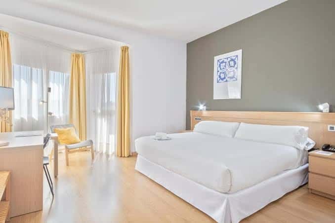 Habitación doble moderna con cama king-size, cortinas amarillas y decoración minimalista
