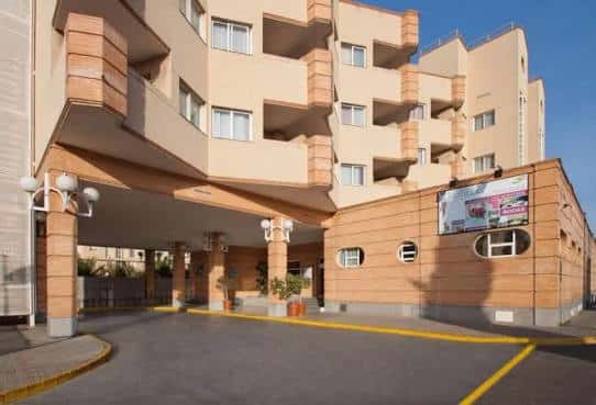Entrada principal del hotel con marquesina y fachada en tonos beige y terracota