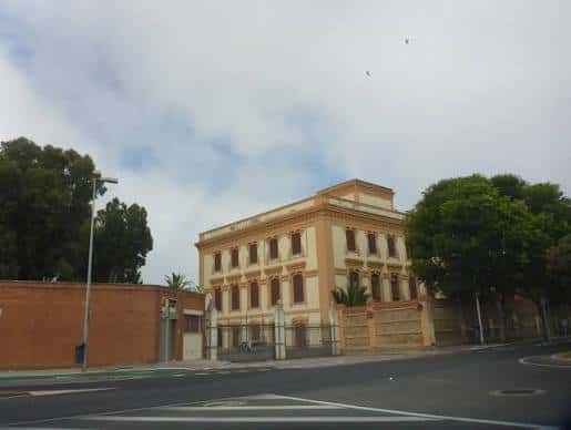 Fachada principal del edificio histórico de los depósitos de tabaco rodeado de árboles
