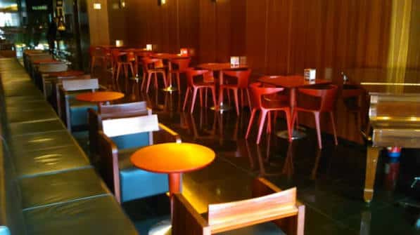 Zona de bar con mesas altas y sillas modernas en ambiente cálido