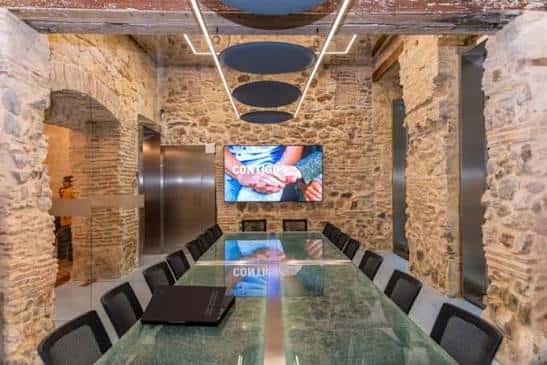 Sala de reuniones moderna con paredes de piedra y mesa de cristal