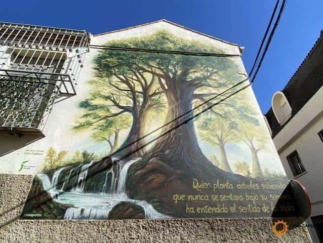 Mural de un árbol frondoso con cascada en la fachada de un edificio