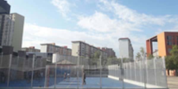 Plaza exterior frente al centro de salud con bancos y árboles en un día soleado