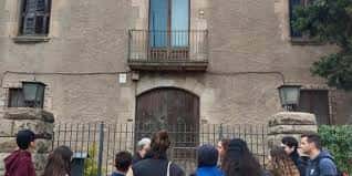 Detalle de la fachada histórica del edificio con balcón y puerta de madera