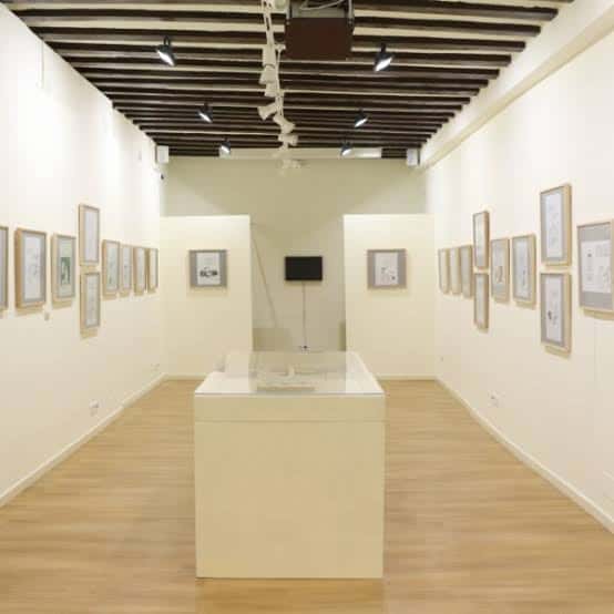 Sala de exposiciones con techos de vigas oscuras y suelo de madera clara