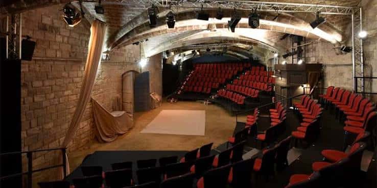 Escenario configurado para evento con alfombra blanca y butacas dispuestas en semicírculo