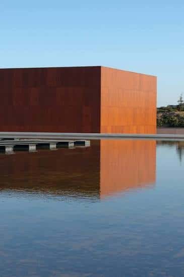Fachada del MUA reflejada en el agua, mostrando su diseño arquitectónico moderno