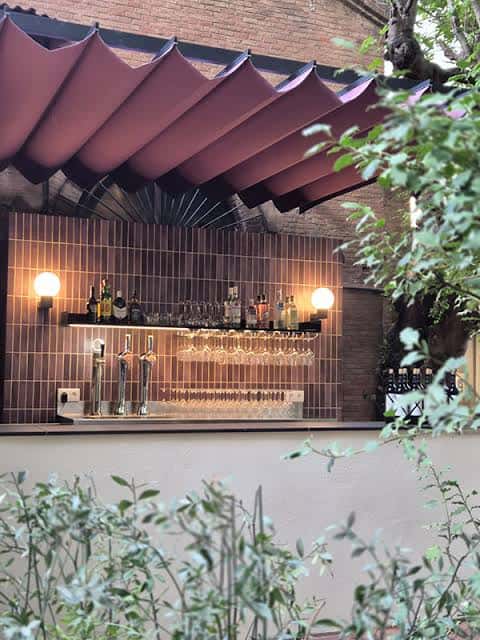 Barra exterior con toldo púrpura y decoración vegetal
