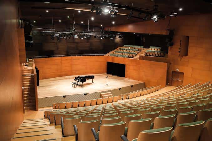 Interior del auditorio con piano en el escenario y butacas vacías