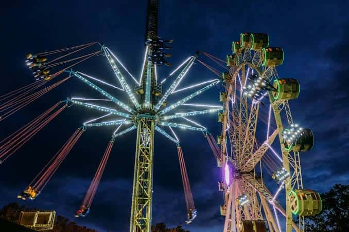 Vista nocturna de atracciones iluminadas en la feria