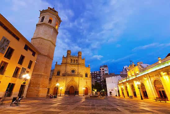 Plaza Mayor de Castellón iluminada al atardecer con la torre del campanario y fachadas históricas