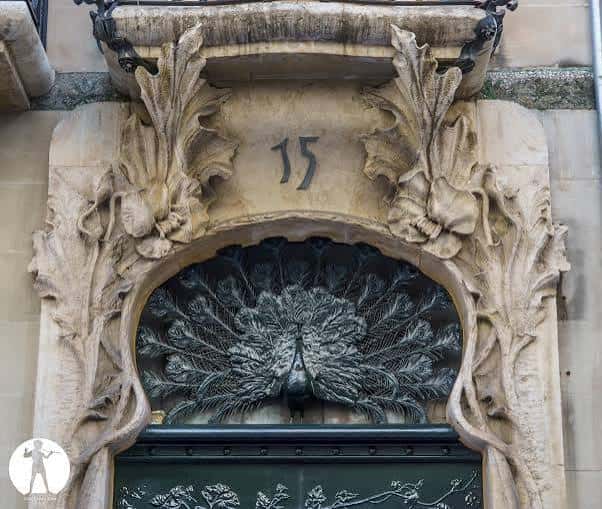 Detalle arquitectónico de la entrada del Estudio Casa del Pavo con escultura de pavo real y número 15