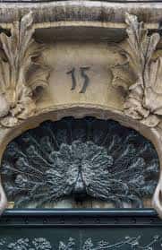 Vista cercana del ornamento floral y el pavo real en la puerta principal del estudio