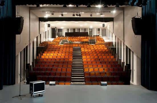 Interior del teatro con disposición de butacas y escenario iluminado