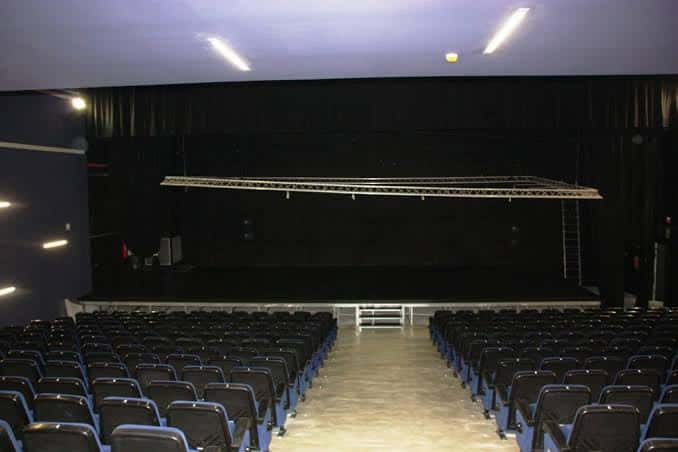 Vista general del auditorio vacío con butacas azules y escenario