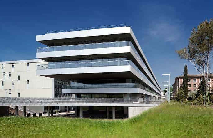 Fachada moderna del edificio principal del campus con balcones de cristal y cielo azul