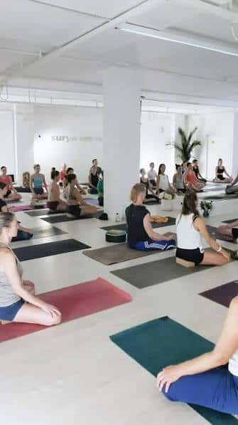 Clase de yoga en Sala Surya: Participantes en sesión grupal sobre esterillas
